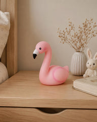 Pink flamingo lamp on wooden bedside table in nursery