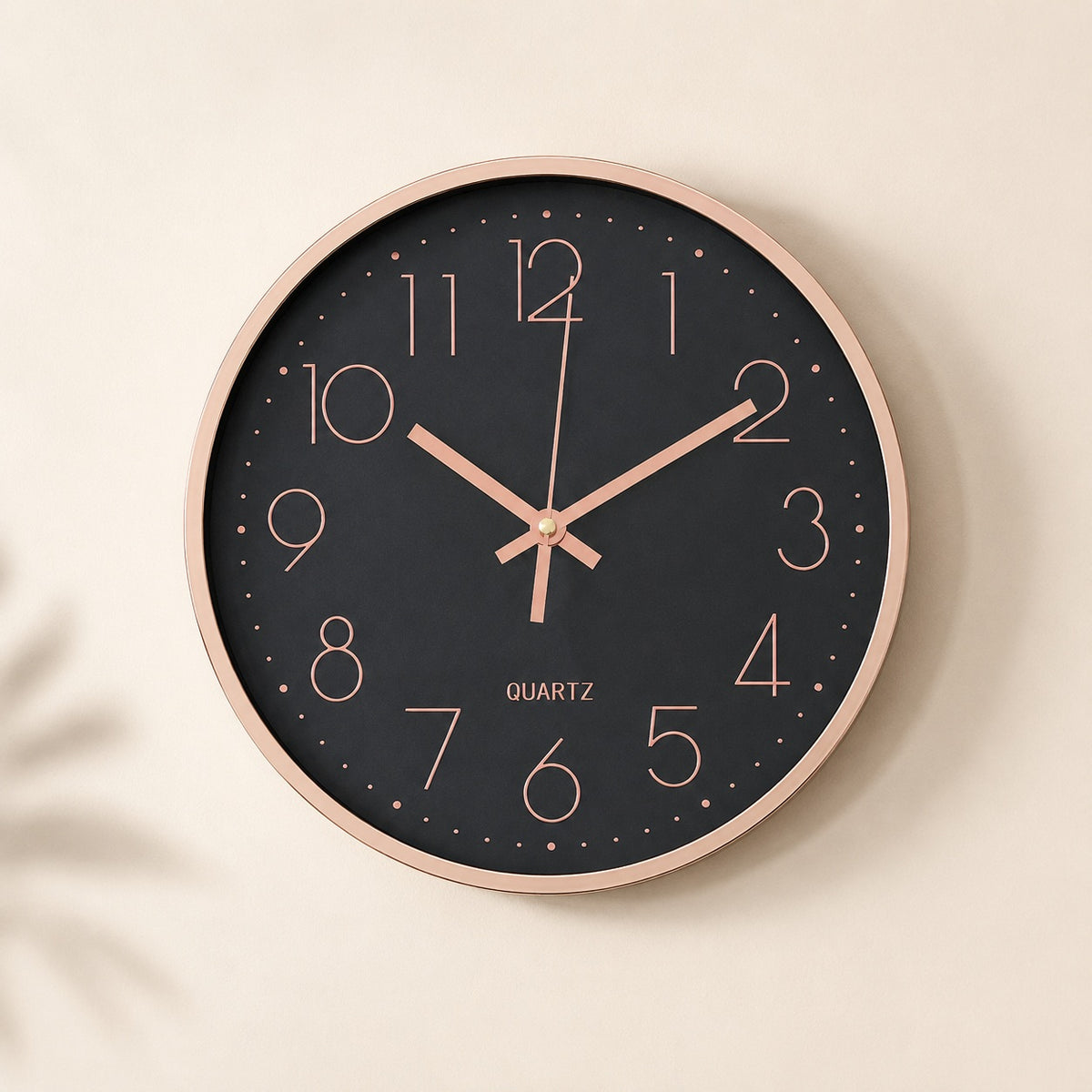 Black wall clock with rose gold numerals and rim on a warm beige background