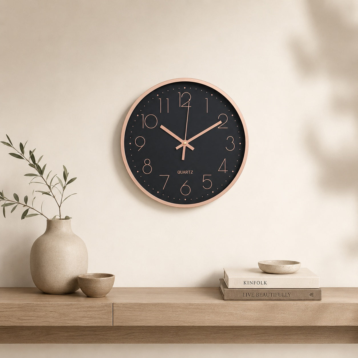 Black and rose gold wall clock above a light wooden console in a calm beige interior