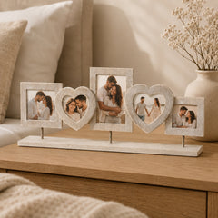 Decorative wooden photo collage frame with heart shapes and couple photos in a warm beige bedroom