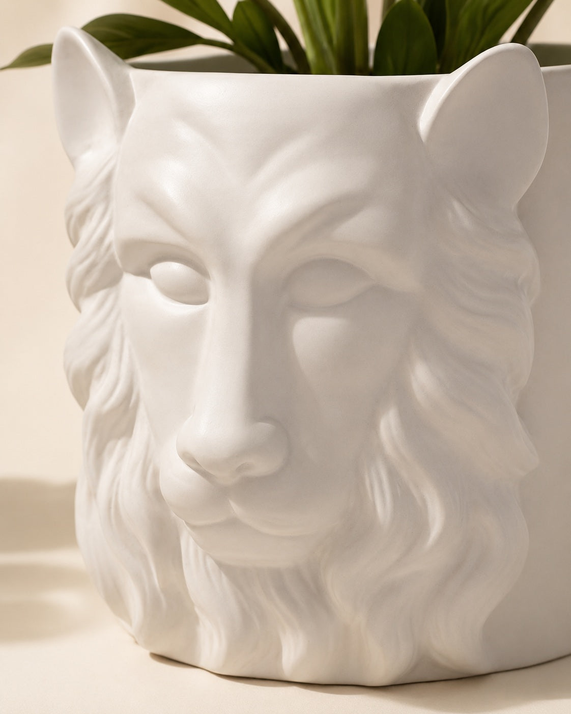 White ceramic planter with sculpted lion head design