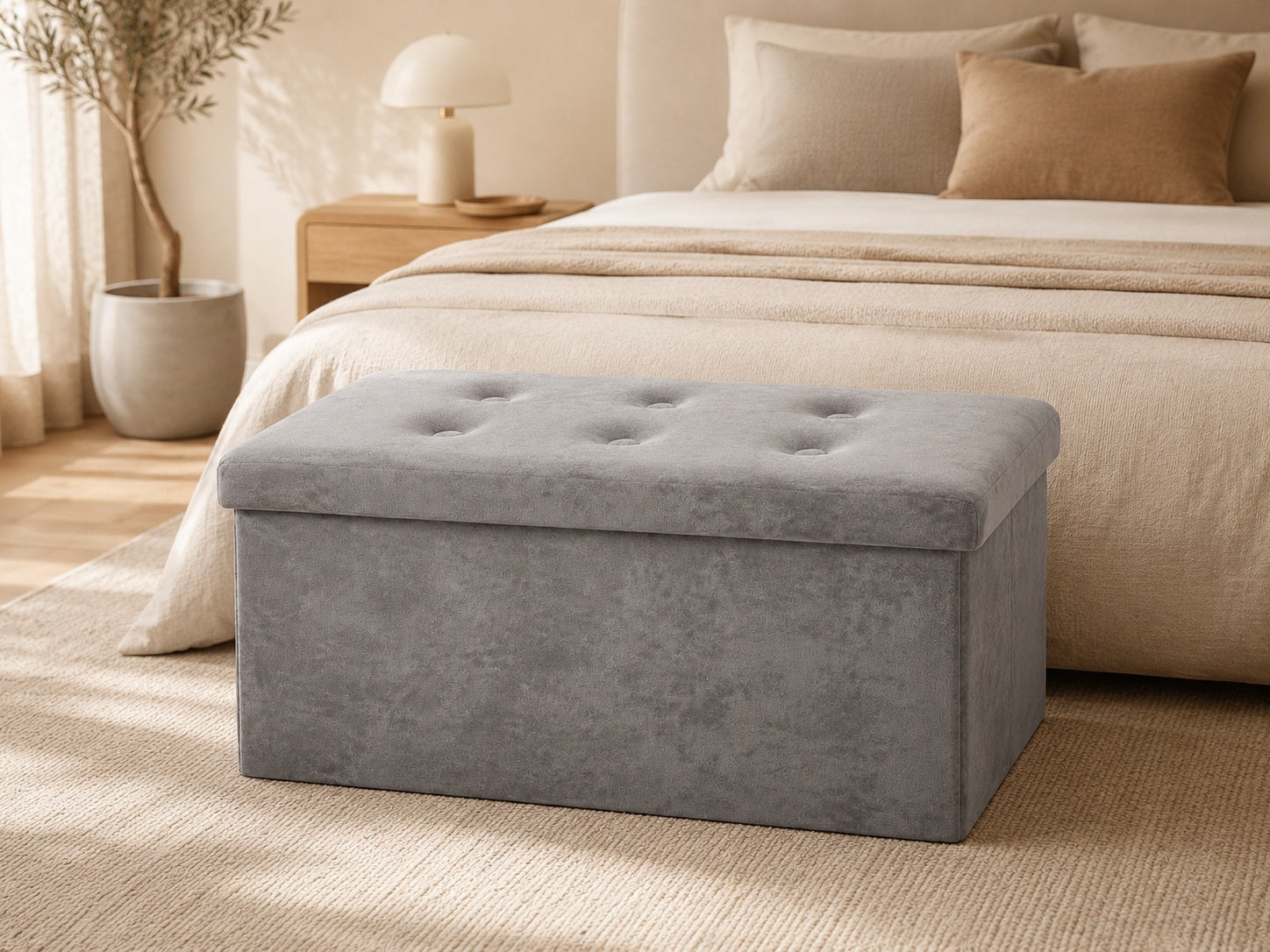 Grey velvet storage bench at the foot of a beige bed
