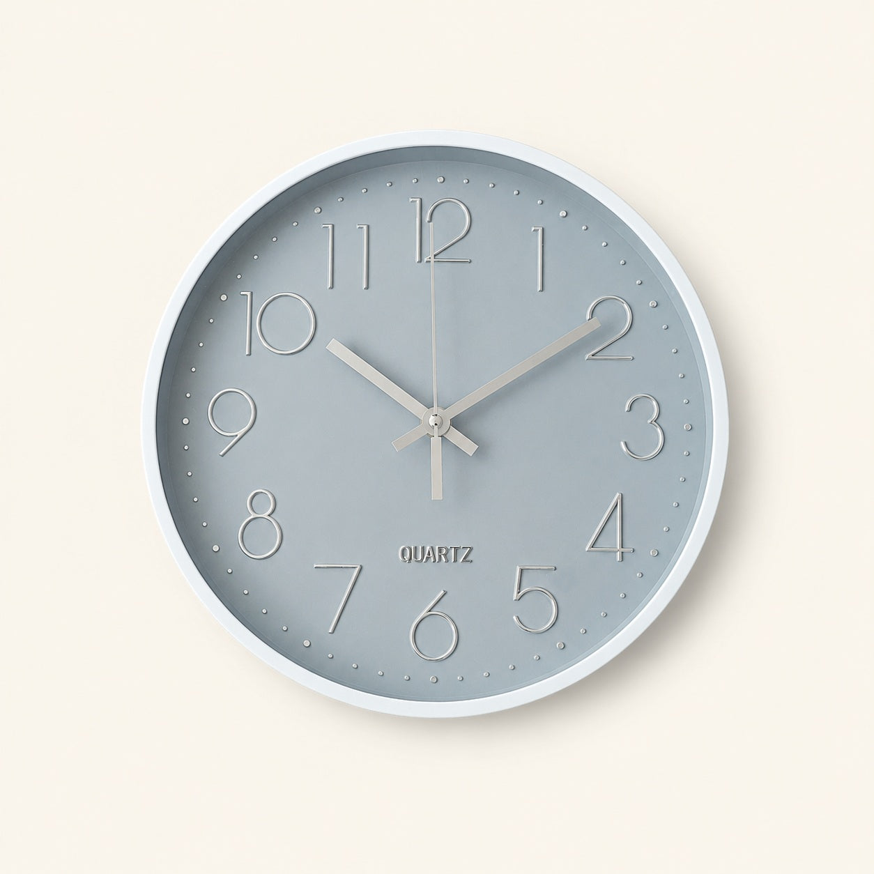 Grey wall clock with silver numerals and white frame on a warm beige background