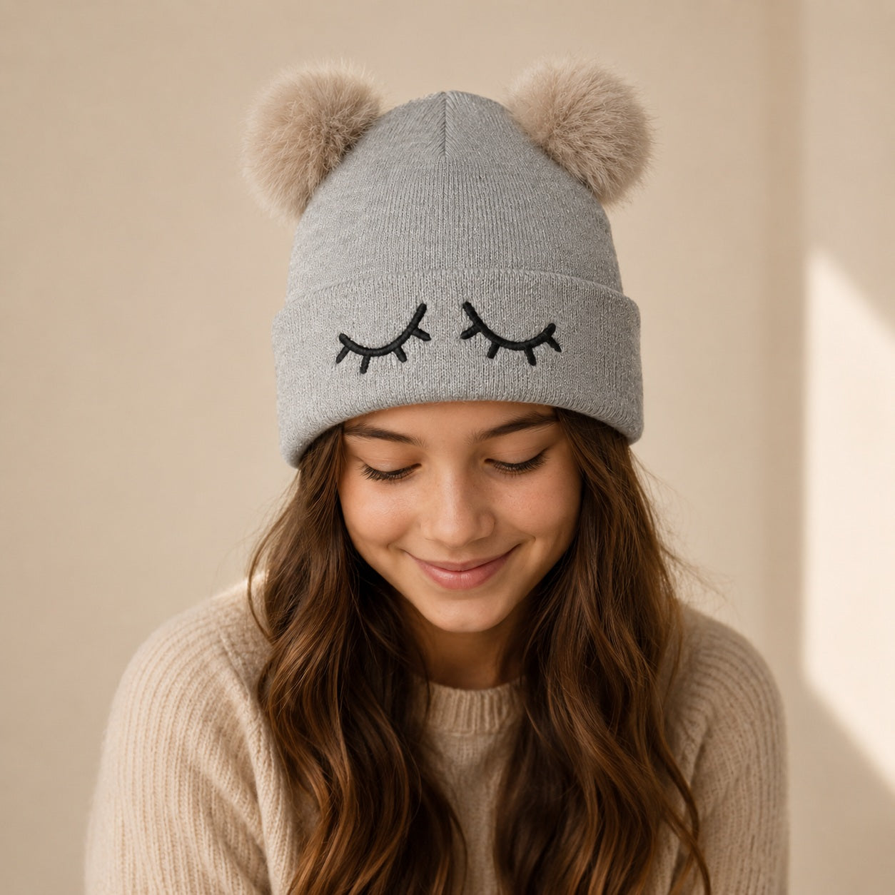 Grijze kindermuts met wimpers en dubbele faux fur pompons