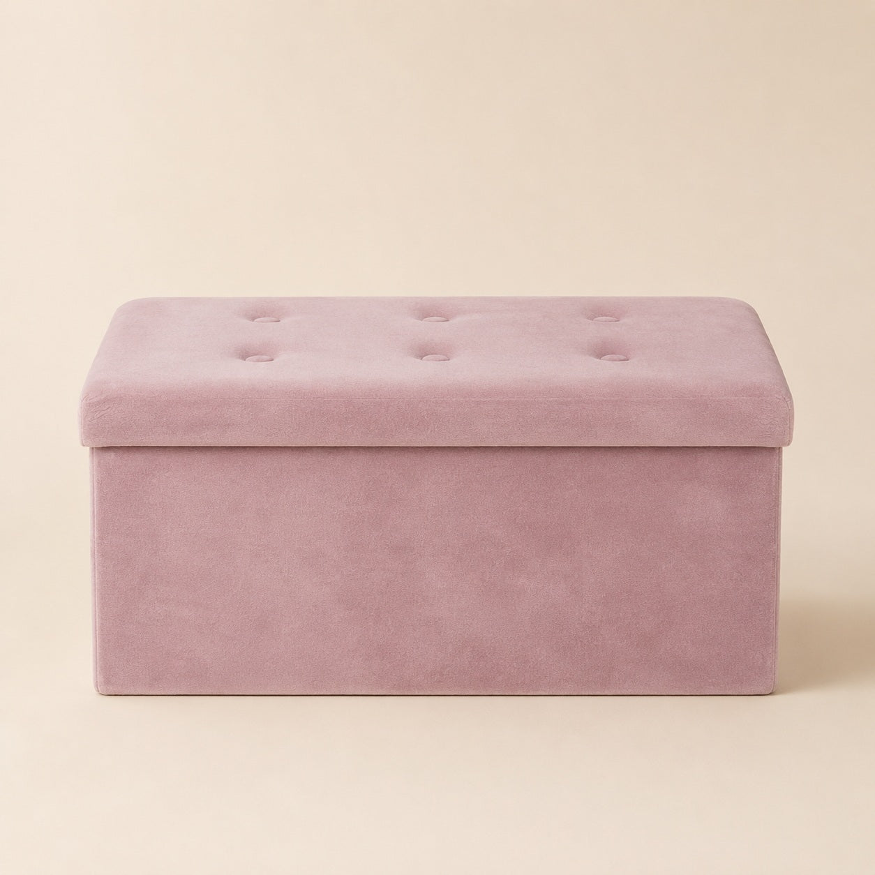 Pink velvet storage bench with tufted lid on a warm beige background