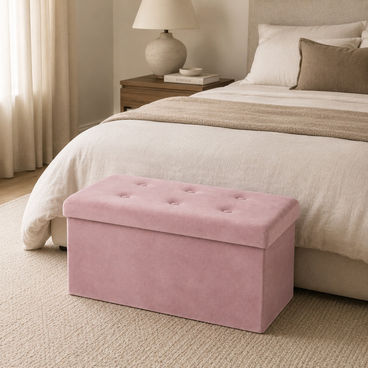 Pink velvet storage bench at the foot of a beige bed