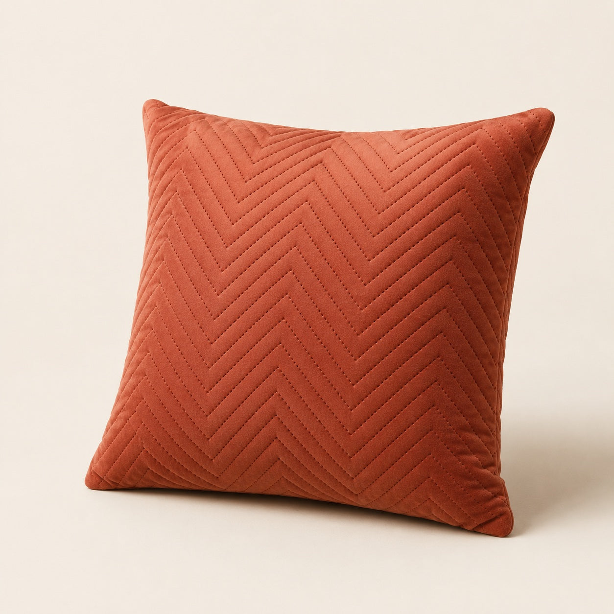 Angled view of terracotta velvet cushion with chevron stitching