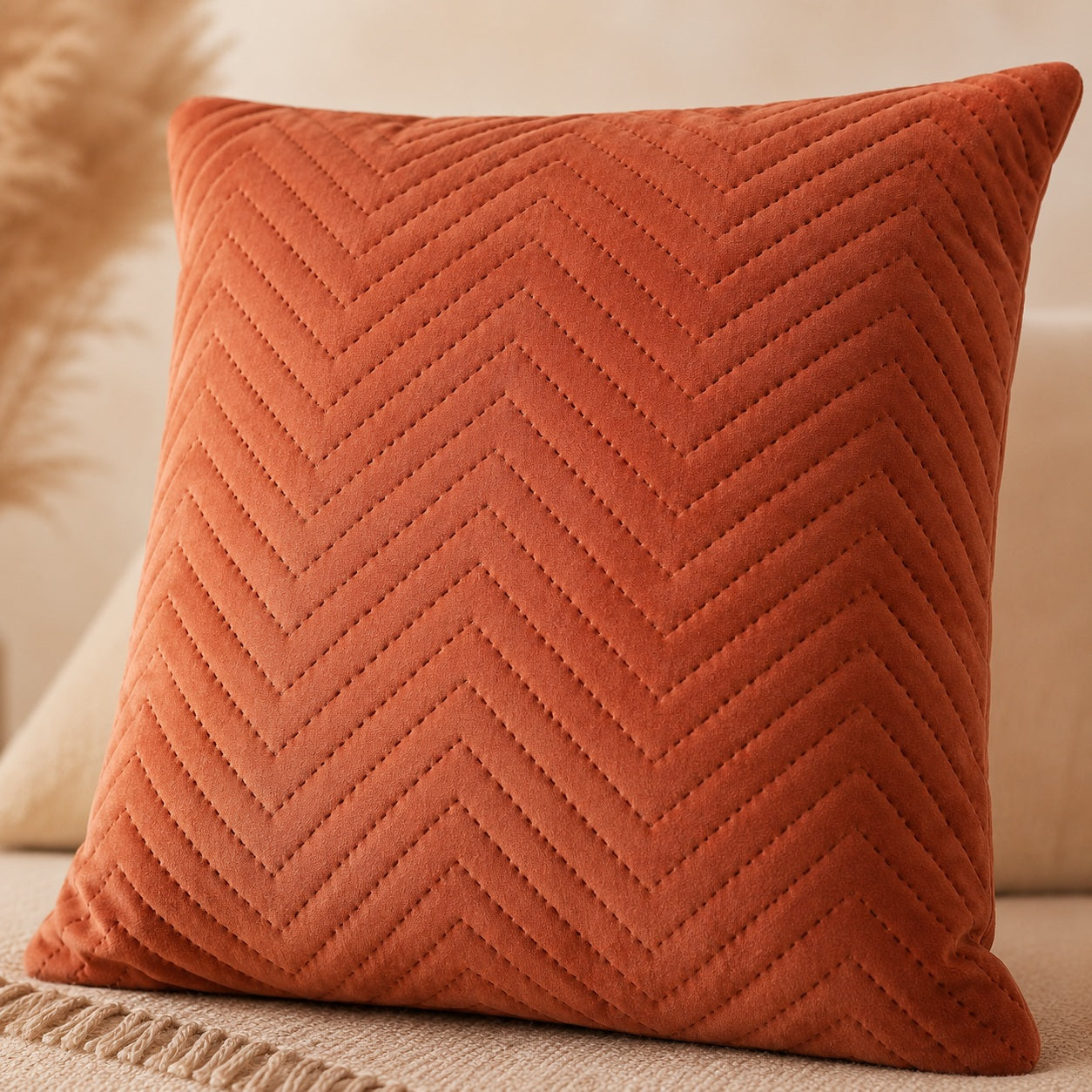 Close-up of soft velvet fabric and stitched chevron pattern on terracotta cushion