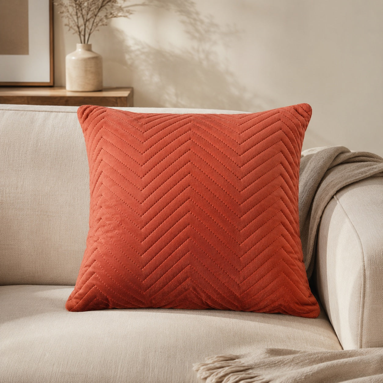 Terracotta chevron cushion styled on a beige armchair in a cosy reading corner
