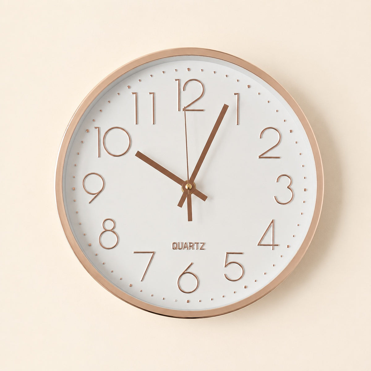 White wall clock with glossy rose gold details on a warm beige background